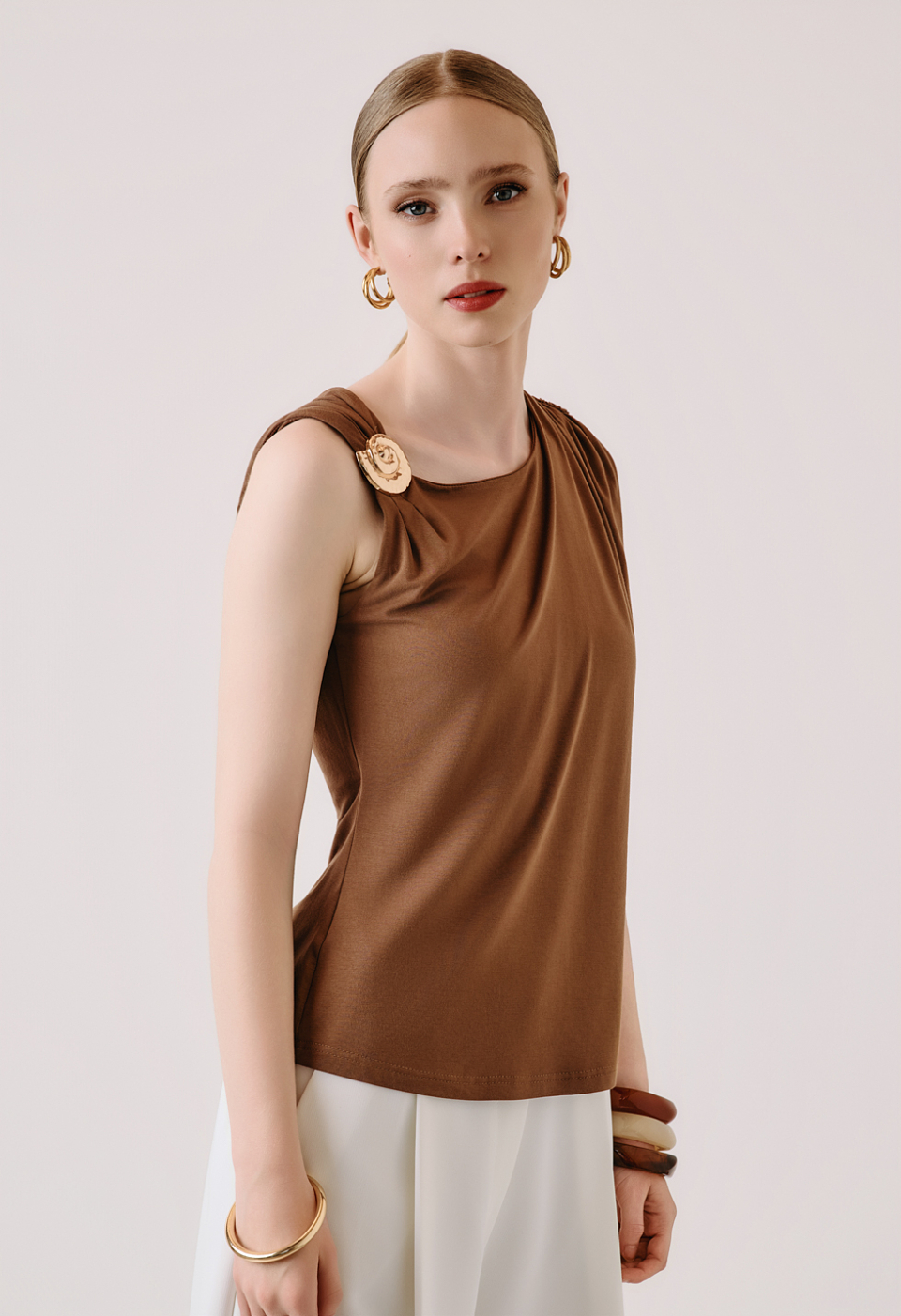 Sleeveless blouse with decorative brooch