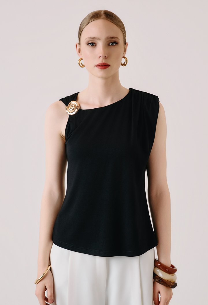 Sleeveless blouse with decorative brooch