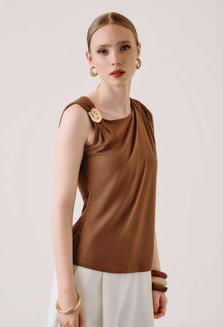 Sleeveless blouse with decorative brooch